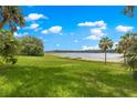 Expansive backyard featuring a pristine lake view, mature palm trees, and lush green grass at 3000 Pine Grove Ln, Lady Lake, FL 32159