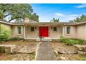 Inviting home entrance with a bright red front door and manicured landscaping at 4025 Ne 18Th St, Ocala, FL 34470