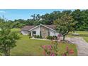 Inviting single-story home with stone accents, mature landscaping, and a circular driveway at 9420 Ne 12Th Ct, Ocala, FL 34479