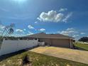 Exterior view of a home showing a paved driveway leading to the garage and a white privacy fence at 10405 Sw 47Th Ave, Ocala, Florida, FL 34476