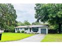 Single-story home with a gray exterior, dark shutters, and a large tree in the front yard at 3610 Sw 25Th Pl, Ocala, FL 34474