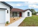 Beautiful single-story home featuring a red front door and stone accents with a well manicured lawn at 6240 Cherry Rd, Ocala, FL 34472