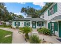Charming exterior view of a white house with green trim, beautifully landscaped with walkways and lush greenery at 7961 Midway Drive Ter # J102, Ocala, FL 34472