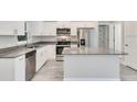 Modern kitchen with stainless steel appliances, granite countertops, white cabinets, and island at 11 Larch Course Ter, Ocala, FL 34480