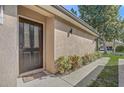 Front door of a tan home with decorative glass, a welcome mat, and green landscaping at 125 Placid Woods Ct, Sanford, FL 32773