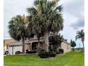 Charming home featuring lush landscaping, mature palm trees, and a well-manicured lawn at 1266 James Island St, The Villages, FL 32162