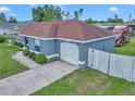 Side angled view of the home displaying the light blue exterior paint, the driveway, and the attached one car garage at 14762 Sw 22Nd Court Rd, Ocala, FL 34473
