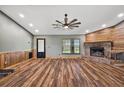 Spacious living room with a brick fireplace, wood paneling, vinyl floors, and a ceiling fan at 15360 Se 73Rd Avenue, Summerfield, FL 34491