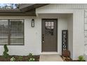 Home entryway featuring a decorative front door, exterior light fixture, and fresh landscaping at 21191 Sw Plantation St, Dunnellon, FL 34431
