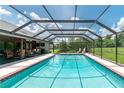 Screened pool area with clear blue water, patio furniture, and a view of the surrounding greenery at 2640 Sw 36Th Ln, Ocala, FL 34471