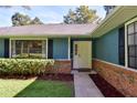 Inviting front entrance with a white door, brick accents, tidy landscaping, and dark window shutters at 2855 Se 38Th St, Ocala, FL 34480
