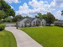 View of the charming single-story home showcasing the driveway, manicured lawn, and partial fence at 3883 Se 51St Ct, Ocala, FL 34480