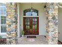 Detailed view of the stone-clad entry with double wood doors and decorative transom window at 3883 Se 51St Ct, Ocala, FL 34480