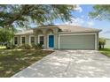 Charming single-story home with a well-manicured lawn, inviting blue door, and attached two-car garage at 4531 Se 27Th St, Ocala, FL 34480