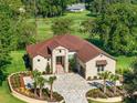 Aerial view showcasing the home's manicured lawn, stone facade, long driveway and proximity to the golf course at 5034 Nw 75Th Ave, Ocala, FL 34482
