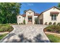 Elegant stucco home featuring a stone facade, paved driveway, and manicured landscaping at 5034 Nw 75Th Ave, Ocala, FL 34482