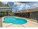 Inviting screened-in pool area with a kidney-shaped pool, surrounded by a spacious patio and secure safety fence at 5390 Se 15Th Ct, Ocala, FL 34480