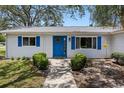 Inviting entrance with a bright blue door, flanked by symmetrical shrubbery and matching blue shutters at 6495 Sw 109Th St, Ocala, FL 34476
