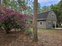 Gambrel-roofed home with white trim, surrounded by vibrant bougainvillea and natural greenery at 9805 Se 182Nd Avenue Rd, Ocklawaha, FL 32179