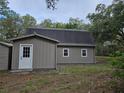 Gambrel-roofed house with white door and trim, offering a serene view of the surrounding trees at 9805 Se 182Nd Avenue Rd, Ocklawaha, FL 32179