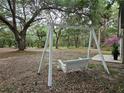 Relaxing backyard featuring a classic white swing set amidst mature trees and lush landscaping at 9805 Se 182Nd Avenue Rd, Ocklawaha, FL 32179