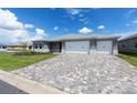 Attractive one-story home boasting a three-car garage and a paver driveway, set against a bright blue sky at 10008 Sw 85Th Place Rd, Ocala, FL 34481