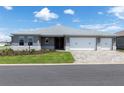Charming one-story home featuring a three-car garage, manicured lawn, and paver driveway under a sunny sky at 10008 Sw 85Th Place Rd, Ocala, FL 34481