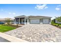 An attractive single-story home featuring a three-car garage, manicured lawn, and patterned brick driveway at 10026 Sw 85Th Place Rd, Ocala, FL 34481