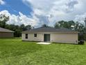 Back exterior showcasing the home's yard and patio with a sliding glass door at 185 Malauka Loop, Ocklawaha, FL 32179