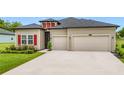 Beautiful home with a manicured lawn, red shutters, and convenient two-car garage at 19424 Sw 77Th Loop, Dunnellon, FL 34432