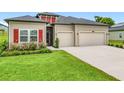 A well-kept home featuring a lush lawn, red accents, and a spacious two-car garage at 19424 Sw 77Th Loop, Dunnellon, FL 34432