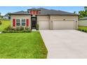 Inviting home with bright red shutters, a well-maintained lawn, and a two-car garage at 19424 Sw 77Th Loop, Dunnellon, FL 34432