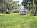 Spacious front yard showcasing a well-maintained lawn, mature trees, and a single-story home at 2131 Ne 145Th Avenue Rd, Silver Springs, FL 34488
