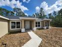 Inviting front entrance of a single-story home with a concrete walkway and covered porch at 23213 Nw Mallard Ave, Dunnellon, FL 34431