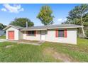View of the exterior elevation of a single story home, red shutters, green lawn and stucco walls at 3428 Ne 17Th Ter, Ocala, FL 34479