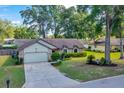 Beautiful home featuring a well-manicured lawn, mature trees, and an attached garage on a bright, sunny day at 5581 Se 35Th St, Ocala, FL 34480