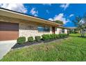 Attractive brick home with manicured landscaping, a well-kept lawn, and a brown garage door at 6142 Se 37Th Ter, Ocala, FL 34480