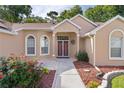 Inviting front entryway with a decorative wreath, tiled walkway, and meticulously manicured landscaping at 11598 Sw 74Th Ct, Ocala, FL 34476