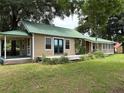 Beautiful exterior of home showcasing light tan siding, a green metal roof and a covered front porch sitting amongst mature trees at 1501 Ne 97Th Street Rd, Anthony, FL 32617
