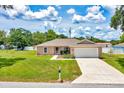 Attractive single-story home with a lush green lawn, sidewalk, and two-car garage on a sunny day at 1689 Ne 161St Pl, Citra, FL 32113