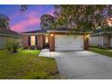 Charming single-story brick home with a well-manicured lawn and a two-car garage at dusk at 2127 Ne 38Th Ter, Ocala, FL 34470