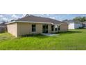 Back exterior view of home that shows a quaint back patio and lawn at 51 Pine Trace Loop, Ocala, FL 34472