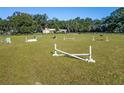 Wide shot of fenced equestrian arena with horse jumps in place on bright green grass at 7563 Nw 21St St, Ocala, FL 34482