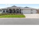 Inviting home with a well-kept lawn, a three-car garage, and stylish stone columns on the front porch at 10032 Sw 85Th Place Rd, Ocala, FL 34481