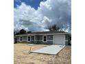 Charming one-story home with a gray exterior, white trim, and a newly-poured concrete driveway at 10385 Se 125Th Ln, Belleview, FL 34420
