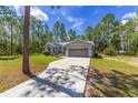 Traditional home shows the driveway that leads to a two-car garage; mature trees in a blue sky at 12320 Sw 62Nd Pl, Ocala, FL 34481