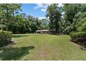 Expansive front yard showcases the home nestled within a lush, green landscape and tall trees at 19130 Nw 60Th Ave, Reddick, FL 32686