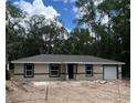New construction home with neutral paint, dark trim, and attached one-car garage in a wooded setting at 20769 Sw Oriole Dr, Dunnellon, FL 34431