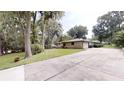 View of home showcasing an expansive driveway and lush greenery surrounding the charming property at 4121 Sw 6Th Ave, Ocala, FL 34471