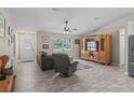 Cozy living room features wood-look tile floors, a ceiling fan, and a large window for natural light at 4660 Se 142Nd Ln, Summerfield, FL 34491